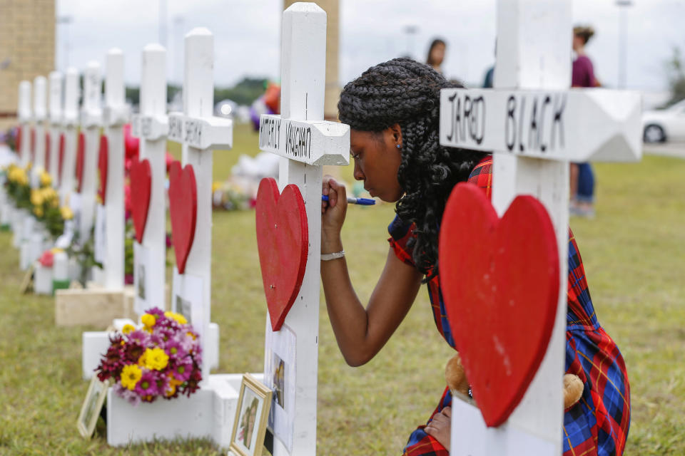 FILE - Santa Fe High School freshman Jai Gillard writes messages on each of the 10 crosses representing victims in front the school in Santa Fe, Texas, May 21, 2018. An emotional audition on “American Idol” by Trey Louis, a survivor of a 2018 Texas high school shooting, prompted tears from the judges as well as criticism of the country’s response to gun violence. Louis was one of the students at Santa Fe High School in May 2018 when another student fatally shot 10 people on campus. (Steve Gonzales/Houston Chronicle via AP, File)
