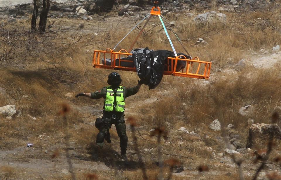 Forensic experts work with several bags of human remains extracted from the bottom of a ravine by a helicopter, which were abandoned at the Mirador Escondido community in Zapopan, Jalisco state, Mexico on May 31, 2023 (AFP via Getty Images)