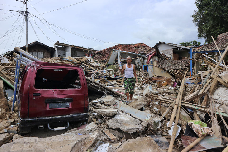 A man walks on the rubble of houses in a neighborhood heavily affected by Monday's earthquake, in Cianjur, West Java, Indonesia, Friday, Nov. 25, 2022. The magnitude 5.6 quake killed hundreds of people, many of them children, and injured thousands. (AP Photo/Rangga Firmansyah)