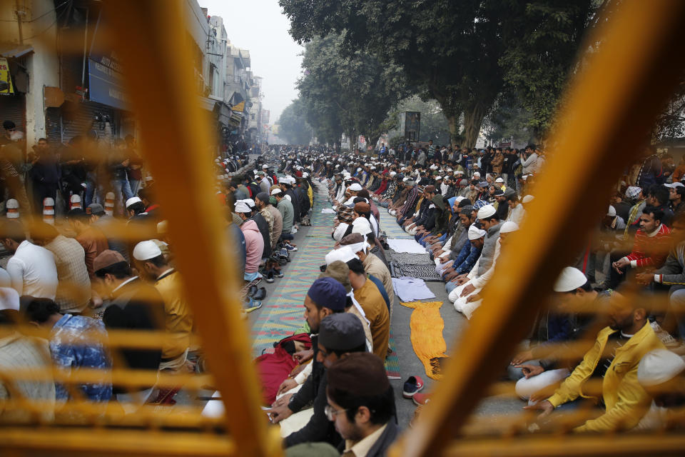 Muslim protesters are seen through a police barricade as they pray on a road near the historic Red Fort in New Delhi, India, Friday, Dec. 20, 2019. Police banned public gatherings in parts of the Indian capital and other cities for a third day Friday and cut internet services to try to stop growing protests against a new citizenship law that have so far left more than 10 people dead and more than 4,000 others detained. (AP Photo/Altaf Qadri)