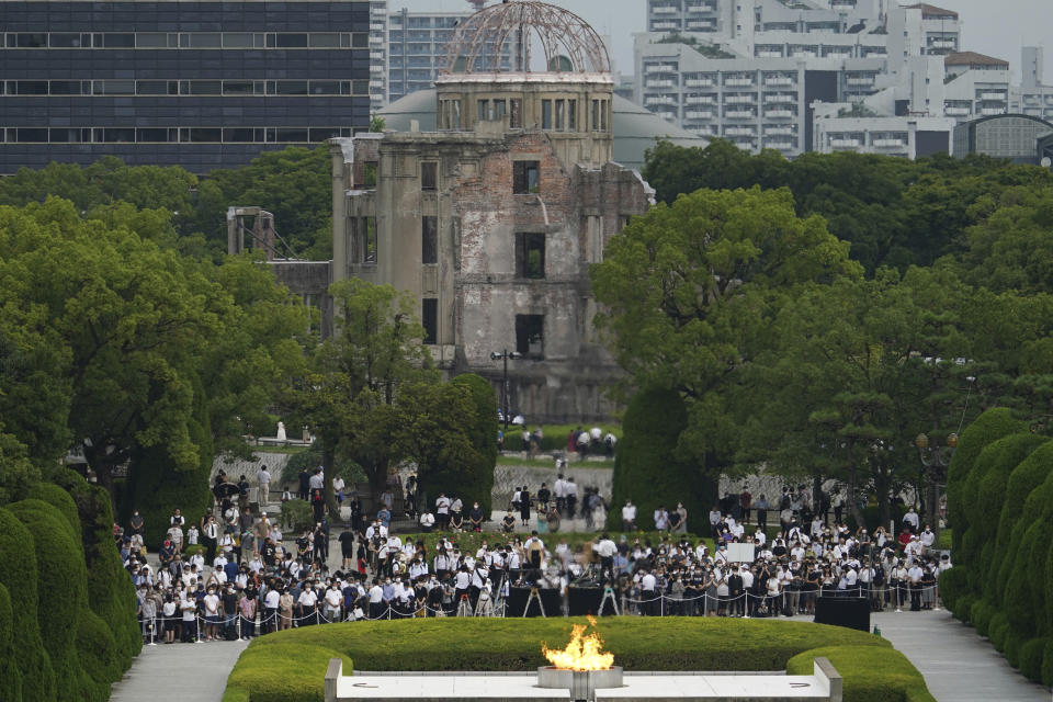 Un grupo de visitantes guardan un minuto de silencio en honor de las víctimas de la bomba atómica que cayó sobre Hiroshima en conmemoración del 75to aniversario de ese ataque, el jueves 6 de agosto de 2020, en Hiroshima, Japón. Al fondo se ve el Memorial de la Paz, las ruinas del único edificio que quedó en pie. (AP Foto/Eugene Hoshiko)