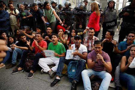 Mourners of the municipal lawmaker Fernando Alban shout slogans in front of riot police members standing outside the headquarters of Bolivarian National Intelligence Service (SEBIN) in Caracas, Venezuela October 8, 2018. REUTERS/Carlos Garcia Rawlins