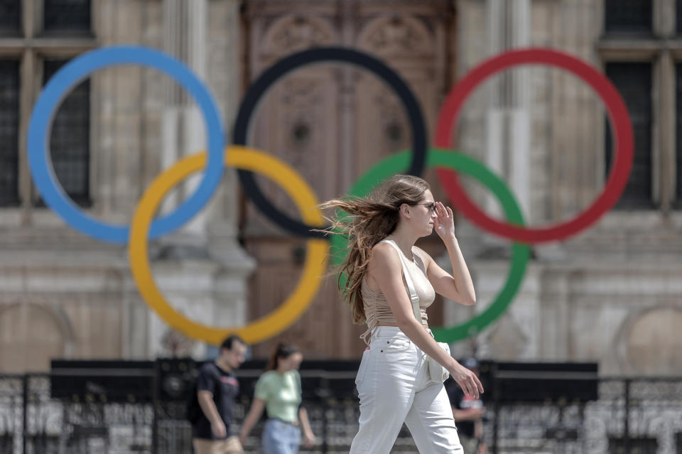 FILE - A woman passes by the Olympic rings at the City Hall in Paris, Monday, July 25, 2022. Paris Olympic organizers appointed prize-winning French theater director Thomas Jolly on Wednesday Sept. 21, 2022 to direct the opening and closing ceremonies of the 2024 Games and Paralympics. (AP Photo/Lewis Joly, File)