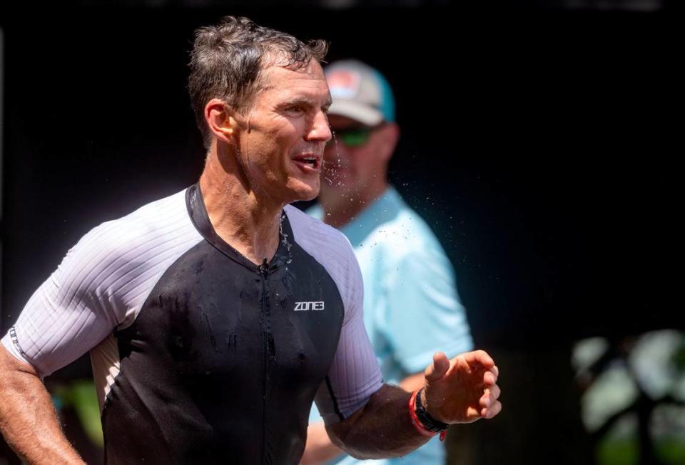 An athlete dumps water on his head as he passes through a water station during the 13.1 mile run in the Ironman 70.3 Pennsylvania Happy Valley on Sunday, June 30, 2024.