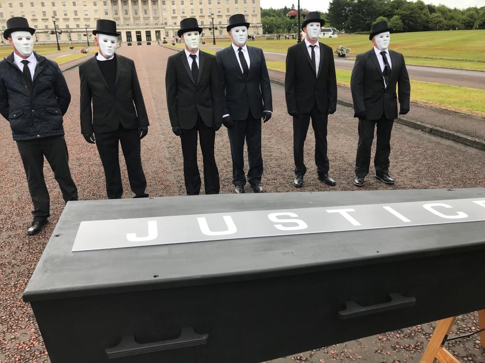 Protesters line up behind a coffin bearing the word ‘justice’ (Jonathan McCambridge/PA)