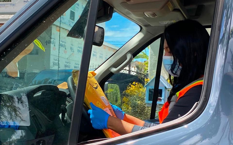 Angela, a delivery worker for Amazon Prime, wears a mask and gloves on her route in Los Angeles on April 8, 2020 - Chris Delmas/AFP