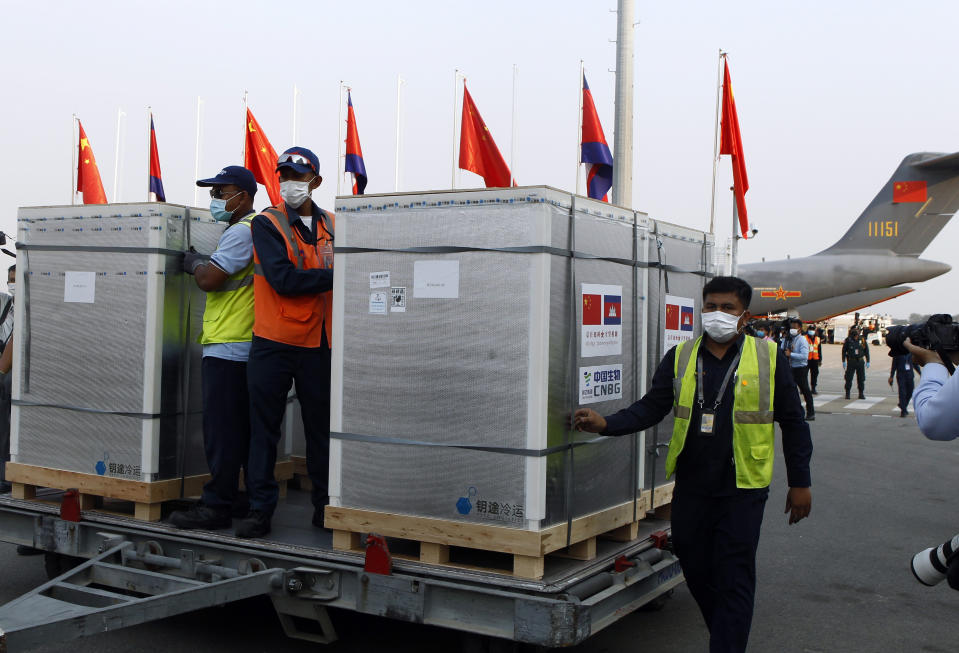 Workers pull boxes loaded with COVID-19 vaccines before a handing over ceremony at Phnom Penh International Airport, in Phnom Penh, Cambodia, Sunday, Feb. 7, 2021. Cambodia on Sunday received its first shipment of COVID-19 vaccine, a donation of 600,000 doses from China, the country's biggest ally. Beijing has been making such donations to several Southeast Asian and African nations in what has been dubbed "vaccine diplomacy," aimed especially at poorer countries like Cambodia. (AP Photo/Heng Sinith)
