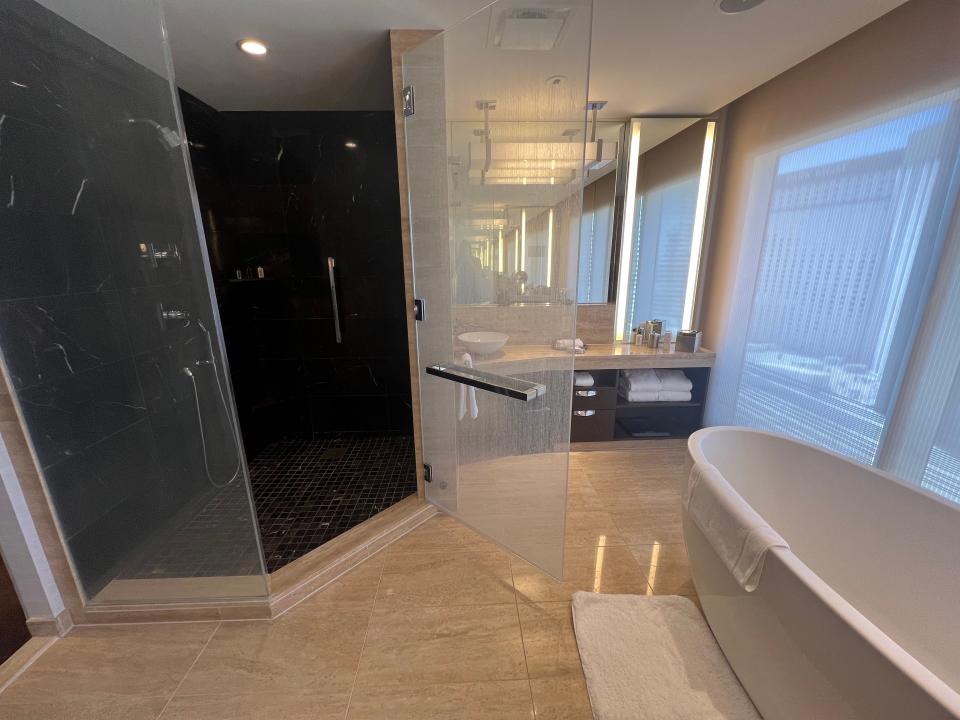 A hotel bathroom with a large walk-in shower and a tub.
