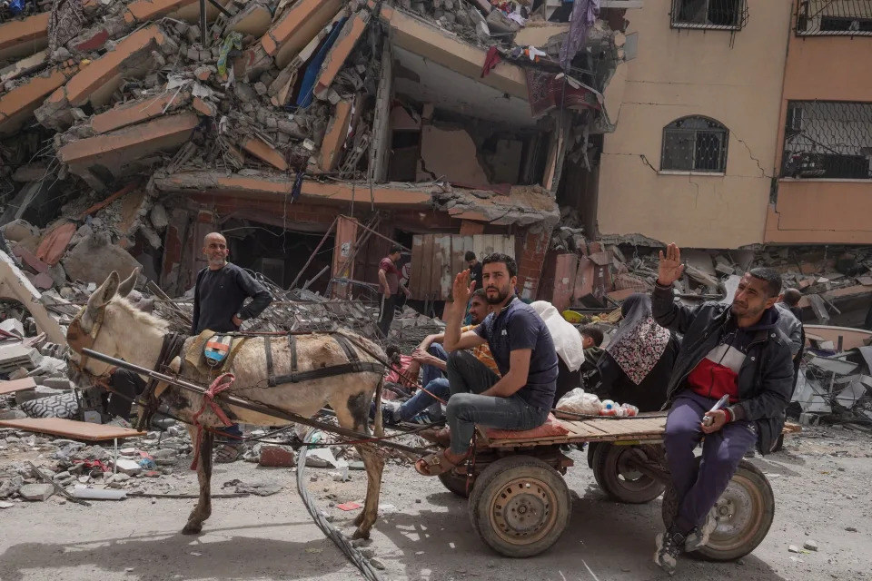 Palestinians sit on the back of a carriage next to a damaged building in the city of Nuseirat in the central Gaza Strip on April 18, 2024.