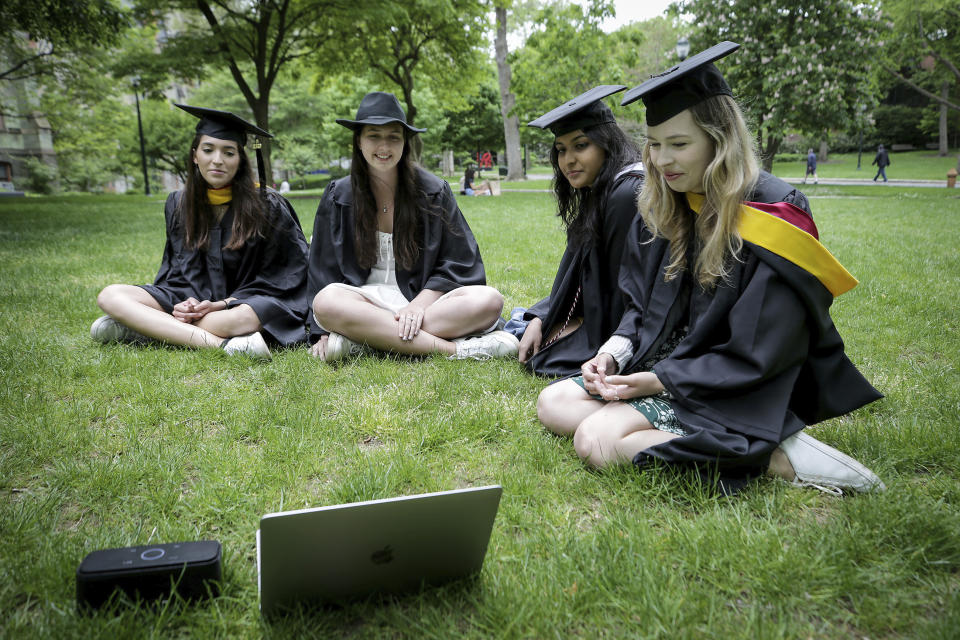 University of Pennsylvania graduates (left to right) Anna Alvarado, Maggie Danaher, Ketaki Gujar, and Megan Spitzer watch Penn's graduation ceremony as they sit on campus in Philadelphia, Pa. on May 18, 2020. Penn held a virtual graduation on Monday. (David Maialetti/The Philadelphia Inquirer via AP)