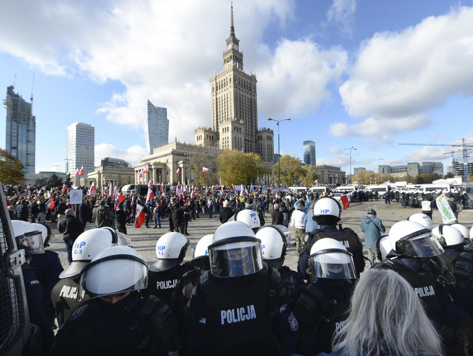 Polish police face protesters, angry over new restrictions aimed at fighting the coronavirus pandemic, in Warsaw, Poland, Saturday, Oct. 24, 2020. The protesters included entrepreneurs, far-right politicians, football fans and vaccine opponents. The clashes come amid rising social tensions and as new restrictions just short of a full lockdown took effect Saturday. (AP Photo/Czarek Sokolowski)