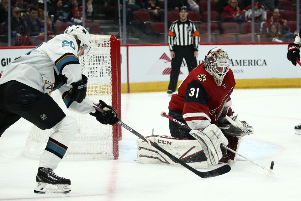 Arizona Coyotes goaltender Adin Hill (31) flips the puck away after a shot from San Jose Sharks left wing Marcus Sorensen (20) during the first period of an NHL hockey game Tuesday, Jan. 14, 2020, in Glendale, Ariz. (AP Photo/Ross D. Franklin)