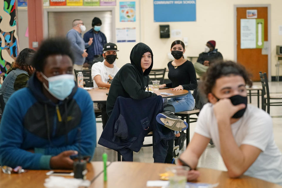 In this Oct. 29, 2020 photo, students at West Brooklyn Community High School listen to questions posed by their principal during a current events-trivia quiz and pizza party in the school's cafeteria in New York. The school recently reopened after a three-week shutdown due to coronavirus cases in the neighborhood. It caters to students who haven't done well elsewhere, giving them a chance to graduate and succeed. (AP Photo/Kathy Willen, File)