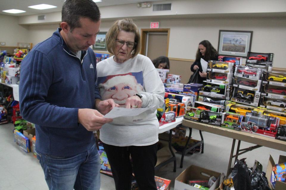 Bret Andorf and Linda Andorf consult their list before picking out toys on Monday, Dec. 4, 2023, for the annual toy drive.