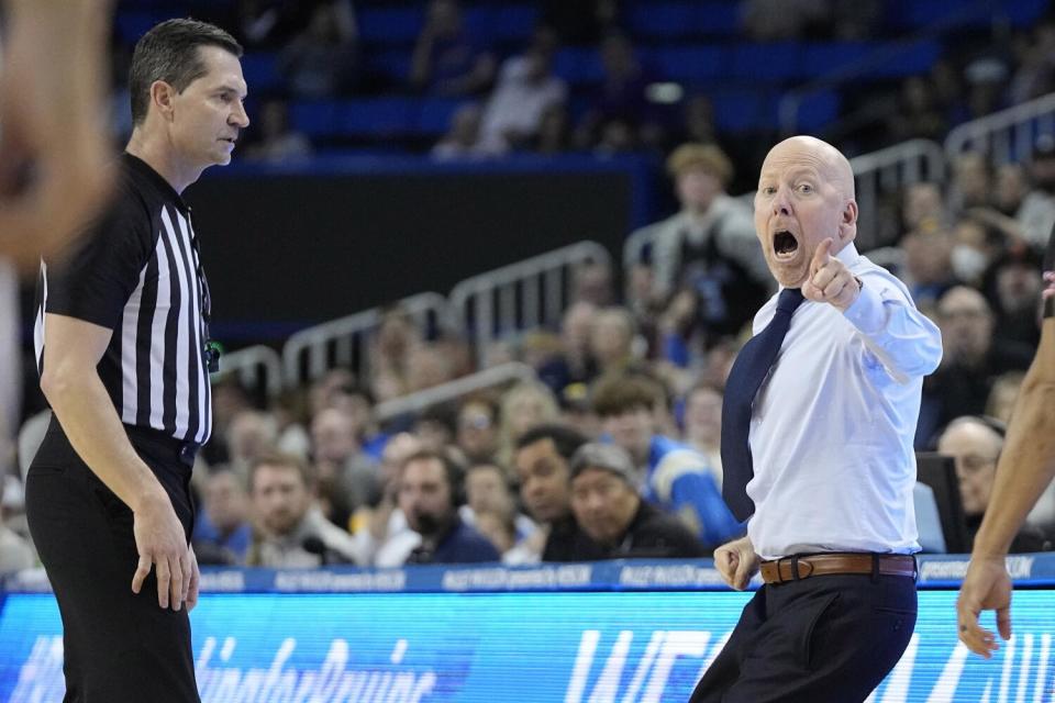 Mick Cronin points and shouts as a referee watches.