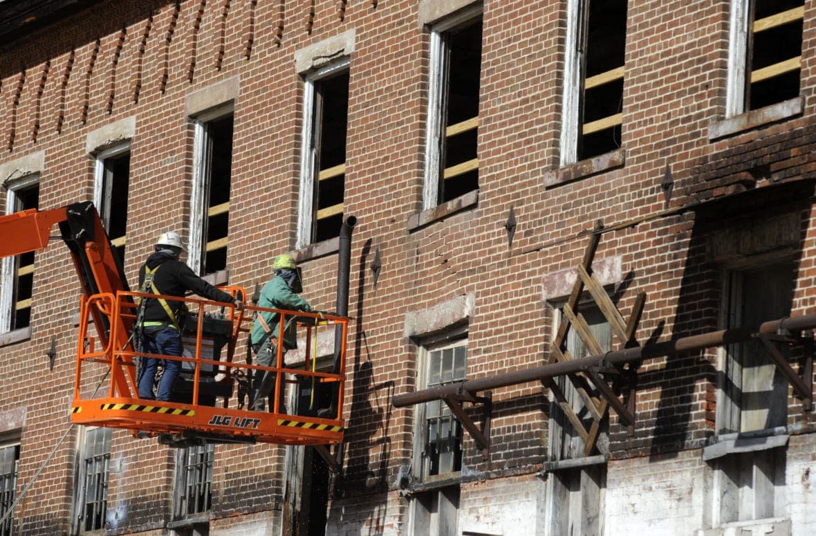 Construction crew members on a lift work on a once-abandoned cotton gin factory that is being renovated into apartments in Prattville, Ala., on Friday, Jan 28, 2022. The factory’s history is tied up in slavery, and the project demonstrates the difficulty of telling complicated U.S. history. (AP Photo/Jay Reeves)