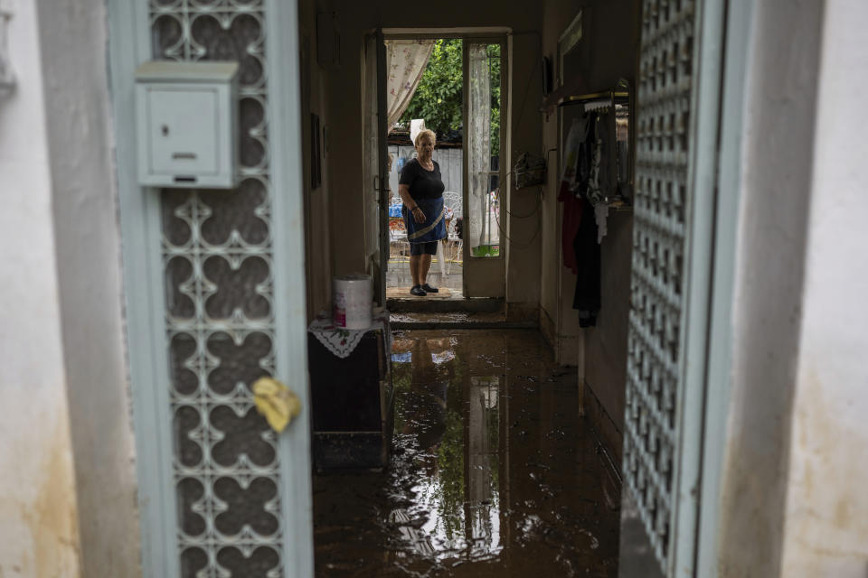 Georgia Sirtarioti, 76, stands at the doorstep of her flooded home in the storm-hit city of Volos, Greece, where power and water outages remained in some districts, on Friday, Sept. 29, 2023. Bad weather has eased in central Greece leaving widespread flooding and infrastructure damage across the farming region that has been battered by two powerful storms in less than a month. (AP Photo/Petros Giannakouris)