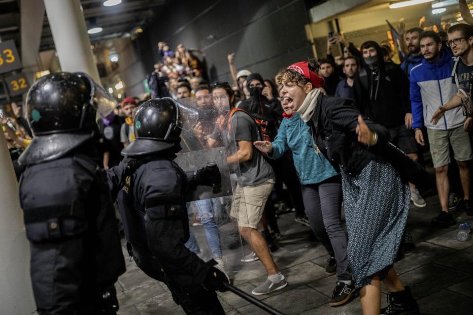 Police scuffle with protesters during a demonstration at El Prat airport, outskirts of Barcelona, Spain, Monday, Oct. 14, 2019. Spain's Supreme Court on Monday sentenced 12 prominent former Catalan politicians and activists to lengthly prison terms for their roles in a 2017 bid to gain Catalonia's independence, sparking protests across the wealthy Spanish region. (AP Photo/Bernat Armangue)