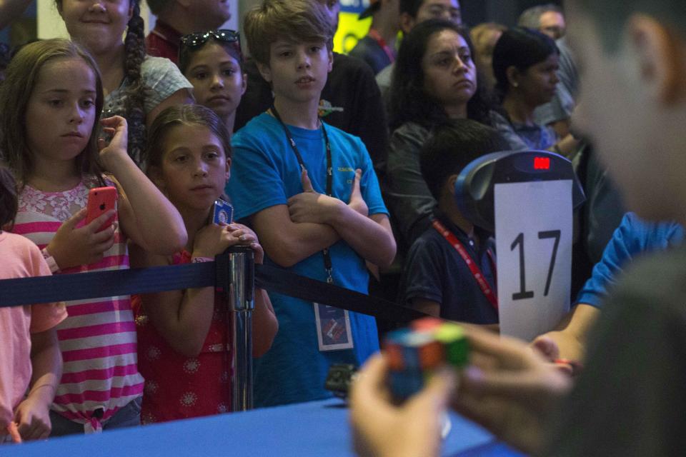 Children watch a competitor at the National Rubik's Cube Championship at Liberty Science Center in Jersey City, New Jersey