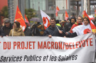 Trade union demonstrators holds a banner that reads " Withdrawal from the Macron and Delovoye project" as they protest in Bayonne, southwestern France, Thursday, Dec. 12, 2019. France's prime minister said Wednesday that the full retirement age will be increased for the country's youngest, but offered concessions in an ill-fated effort to calm a nationwide protest against pension reforms that critics say will erode the nation's way of life. (AP Photo/Bob Edme)