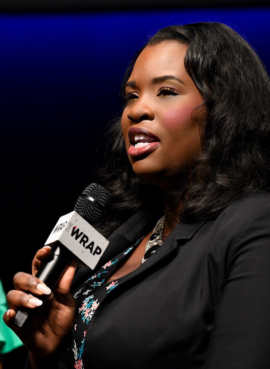 A woman wearing a black shirt holds a microphone