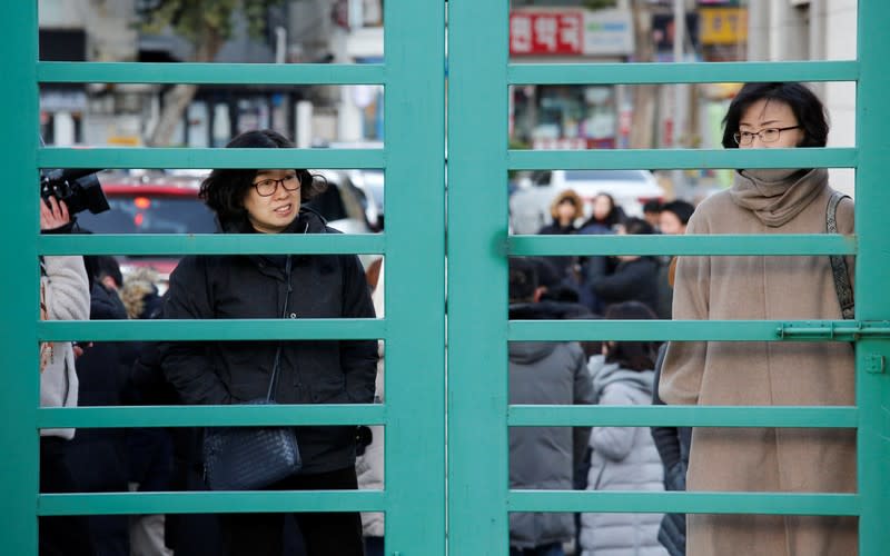 Mothers stand outside an entrance as their children get to the venue for taking the annual college entrance examinations, in front of an exam hall in Seoul