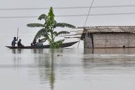 Villagers paddle their boat next to a partially submerged hut in the flood affected area of Hatishila, in Kamrup district of Assam state on July 14, 2020. Flooding is an annual phenomenon in India's northeast, claiming hundreds of lives each year. (Photo by BIJU BORO/AFP via Getty Images)