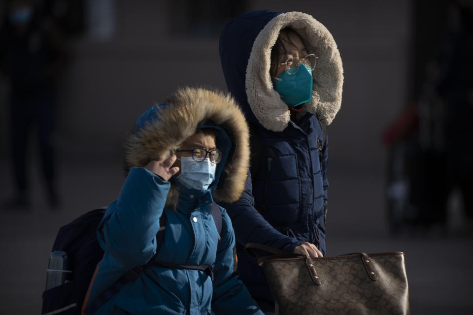 Travelers wearing face masks walk toward the entrance of the Beijing Railway Station in Beijing, Saturday, Jan. 14, 2023. Millions of Chinese are expected to travel during the Lunar New Year holiday period this year. (AP Photo/Mark Schiefelbein)