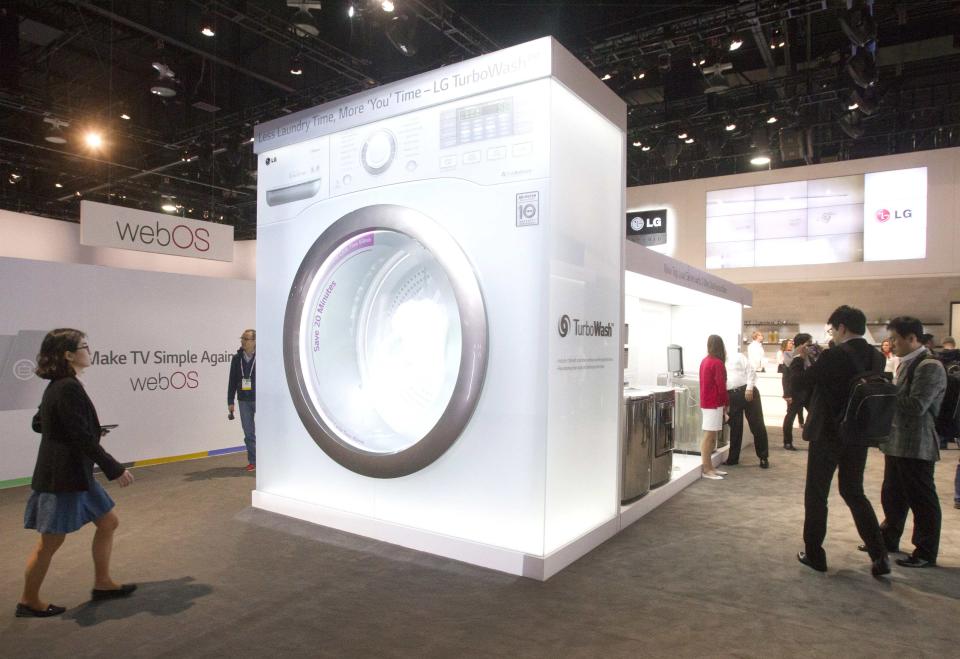 People pass by an oversize mockup of an LG Electronics washer at the LG booth during the 2014 International Consumer Electronics Show (CES) in Las Vegas, Nevada, January 7, 2014. REUTERS/Steve Marcus (UNITED STATES - Tags: BUSINESS SCIENCE TECHNOLOGY)