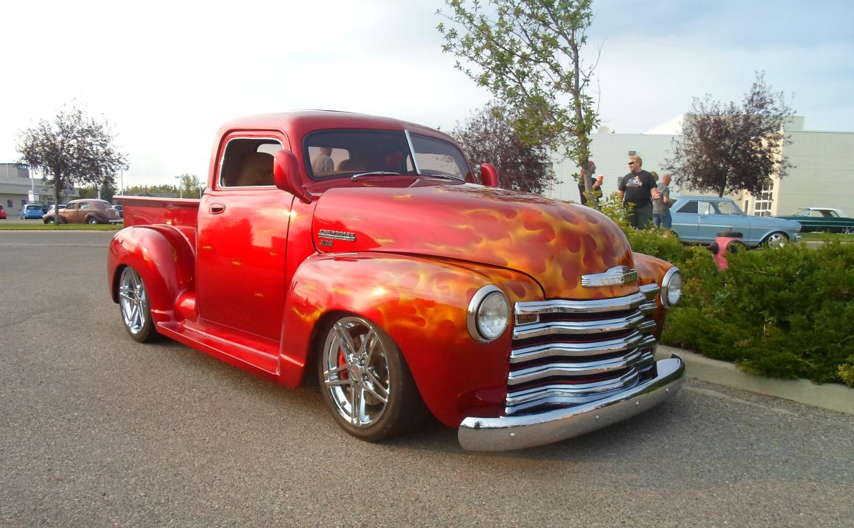 Red 1950 Chevrolet 3100 in a parking lot on a summer day