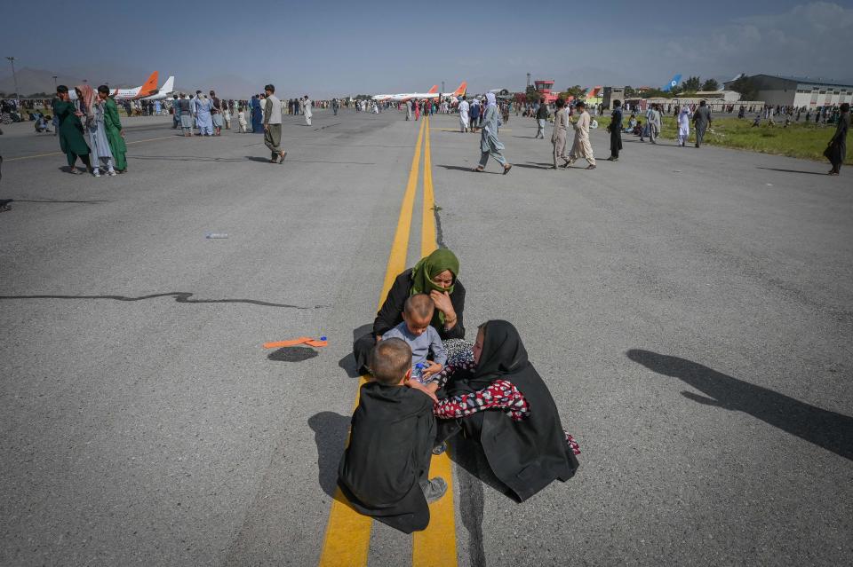 未能登機的婦孺，只能無奈地坐在機場上痛哭。 (Photo by Wakil Kohsar / AFP)