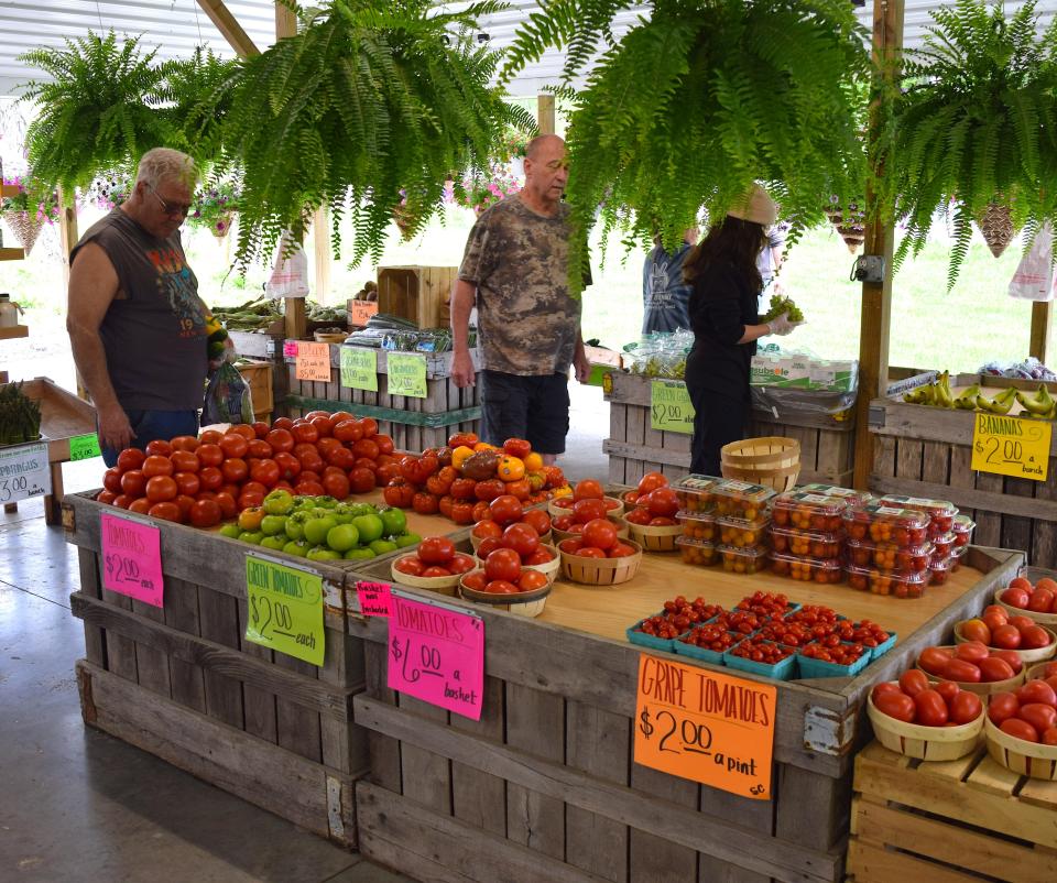 Customers look over the stock of fruits and vegetables available at Harvey's Market.