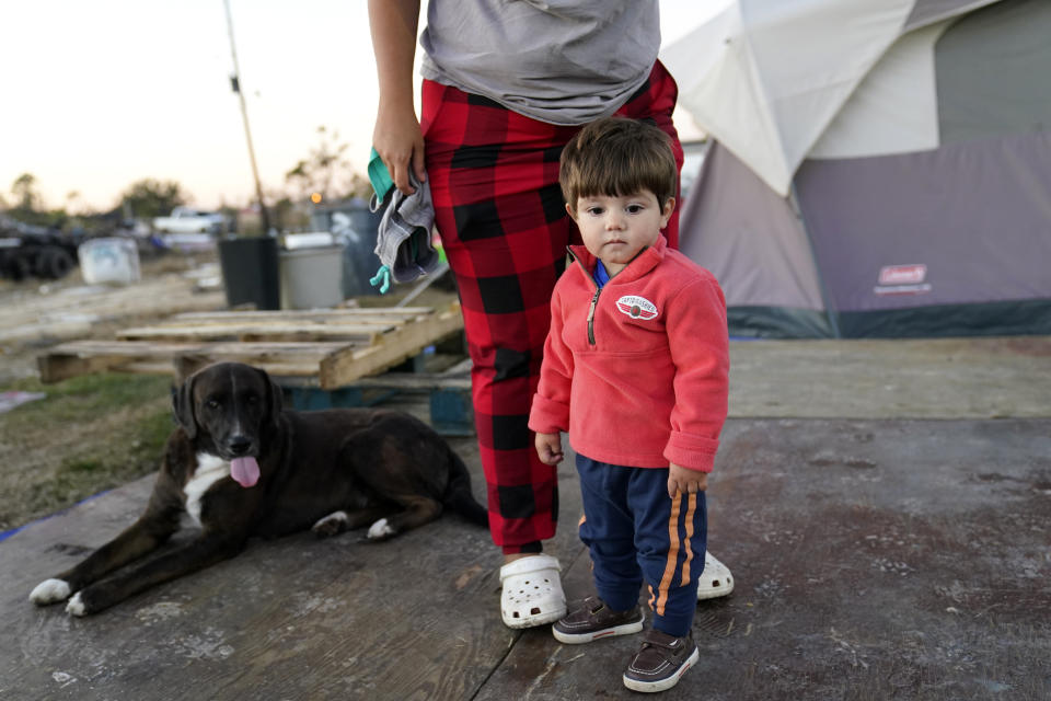 Katelyn Smith stands with her one year old son Ricky Trahan, III, as she prepares to change his clothes, as their family lives in a camper and tents where their home was destroyed, in the aftermath of Hurricane Laura and Hurricane Delta, in Lake Charles, La., Friday, Dec. 4, 2020. (AP Photo/Gerald Herbert)