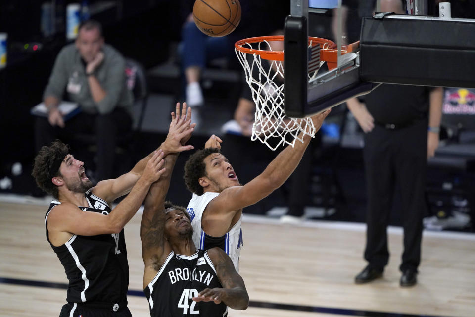 Orlando Magic's Aaron Gordon, right, watches a rebound with Brooklyn Nets' Lance Thomas (42) and Joe Harris, left, during the second half of an NBA basketball game Friday, July 31, 2020, in Lake Buena Vista, Fla. (AP Photo/Ashley Landis, Pool)