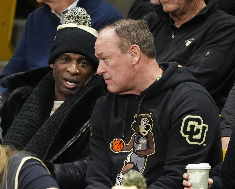 Colorado football coach Deion Sanders, left, chats with athletic director Rick George duirng the first half of an NCAA college basketball game between Colorado and Southern California on Saturday, Jan. 13, 2024, in Boulder, Colo. (AP Photo/David Zalubowski)