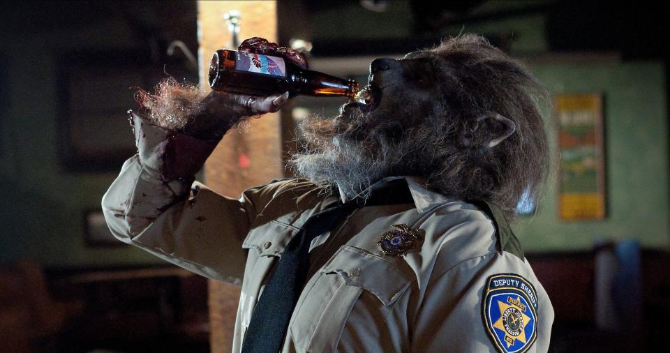 A werewolf in a police uniform drinks a beer