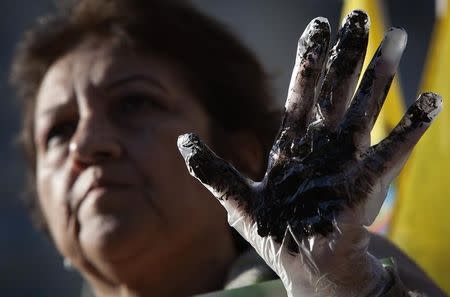 A protester from Ecuador holds up an oil covered hand as she demonstrates against Chevron's Racketeer Influenced and Corrupt Organizations (RICO) trial in New York, October 15, 2013. REUTERS/Carlo Allegri