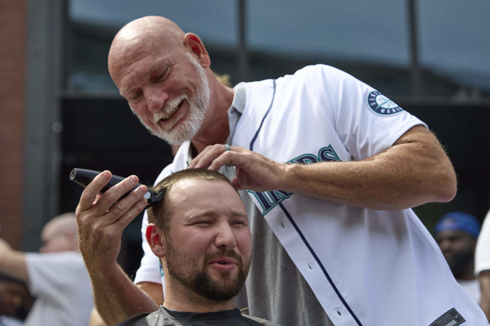 Seattle Mariners catcher Cal Raleigh has his head shaved by former Mariner Jay Buhner on Buhner Buzz Night, Thursday, June 13, 2024, in Seattle. The promotion is based on former Buhner's shaved-head style. (AP Photo/John Froschauer)