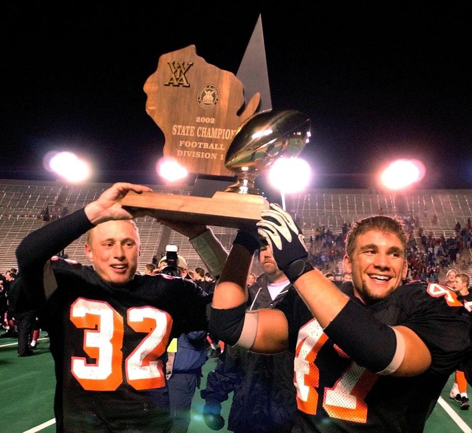 Marshfield's Andy Mikula (32) and Dane Cordes (47) hold up the WIAA Div. 1 championship trophy Friday, Nov. 22, 2002, in Madison, Wis. Marshfield beat Arrowhead, 20-14.