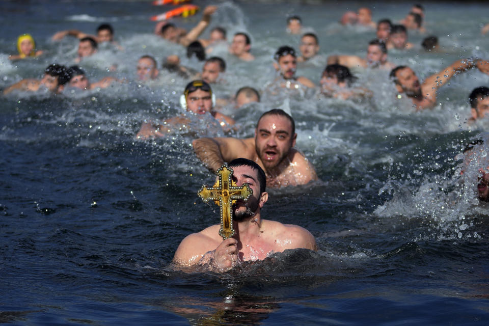 Greek Orthodox faithful holds up a wooden crucifix after retrieving it in the Golden Horn during Epiphany day in Istanbul, Turkey, Saturday, Jan. 6, 2024. By tradition, a crucifix is cast into the waters of a lake or river, and it is believed that the person who retrieves it will be freed from evil spirits and will be healthy throughout the year. (AP Photo/Khalil Hamra)