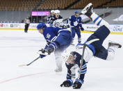 Toronto Maple Leafs right wing Mitchell Marner (16) scores on an empty net and takes a hit from Winnipeg Jets defenseman Neal Pionk (4) during third-period NHL hockey game action in Toronto, Ontario, Monday, Jan. 18, 2021. (Nathan Denette/The Canadian Press via AP