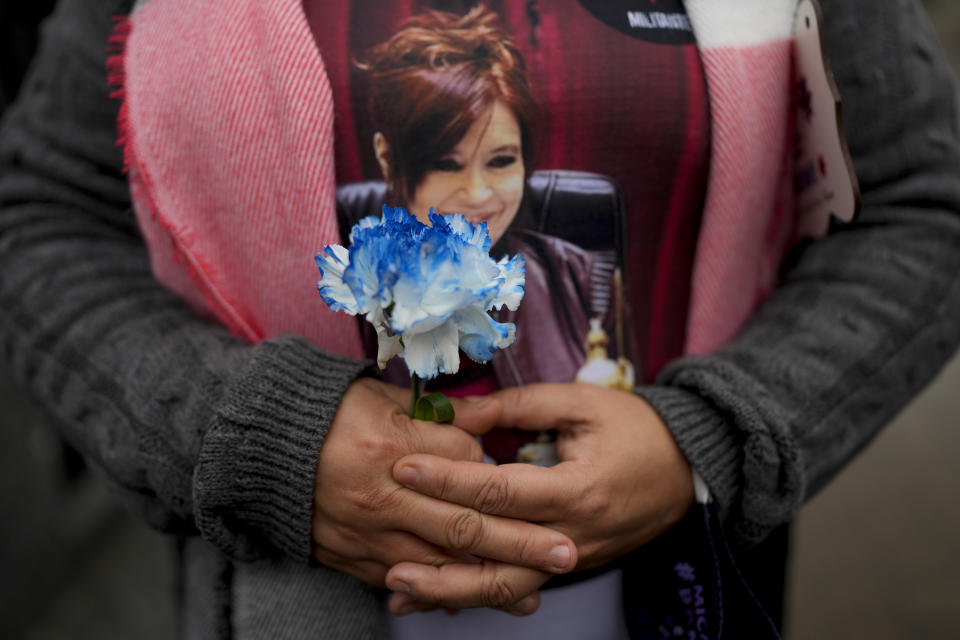 A woman wears a T-shirt of Vice President Cristina Fernandez and holds a flower as she waits her turn to visit the tomb of Argentina's former first lady Maria Eva Duarte de Peron, better known as Evita, in Buenos Aires, Argentina, Tuesday, July 26, 2022. Argentines commemorate the 70th anniversary of the death of their most famous first lady, who died of cancer on July 26, 1952 at the age of 33. (AP Photo/Natacha Pisarenko)