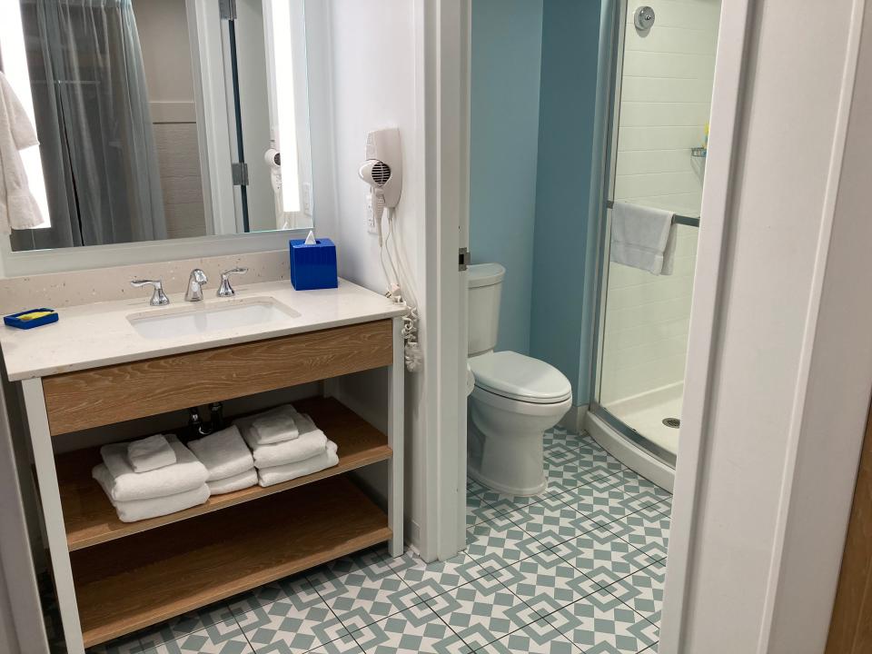 vanity area in bathroom and toilet + shower in the background in standard room