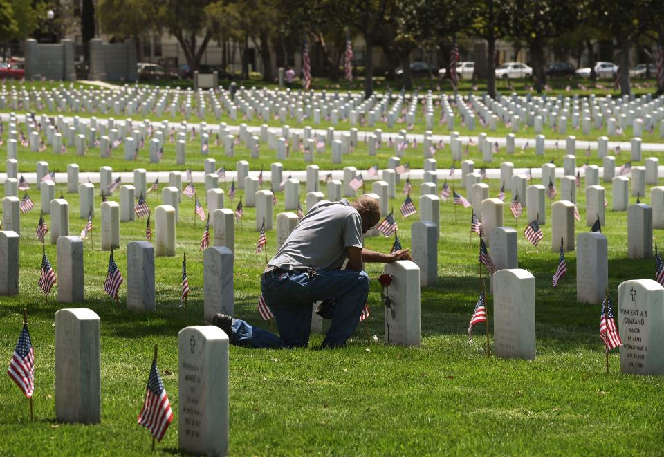 <p>Navy veteran Richard Jones prays before the grave of his friend James McDermott at the Los Angeles National Military Cemetery two days prior to Memorial Day in Los Angeles, Calif., on May 26, 2018. (Photo: Mark Ralston/AFP/Getty Images) </p>