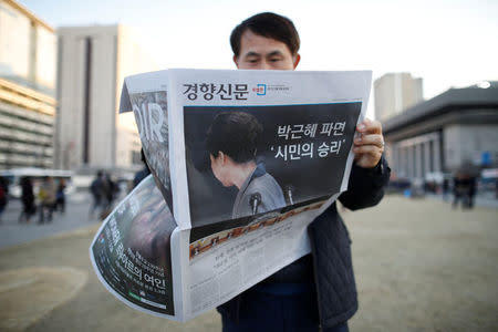 A man reads a newspaper as he attends a rally calling for impeached President Park Geun-hye's arrest in central Seoul, South Korea, March 10, 2017. The headline of the newspaper reads "Expulsion of Park Geun-hye, People's victory". REUTERS/Kim Hong-Ji