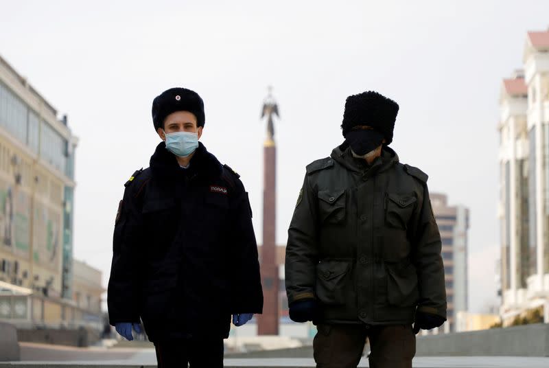 FILE PHOTO: A police officer and a cossack wearing protective masks patrol the territory in Stavropol