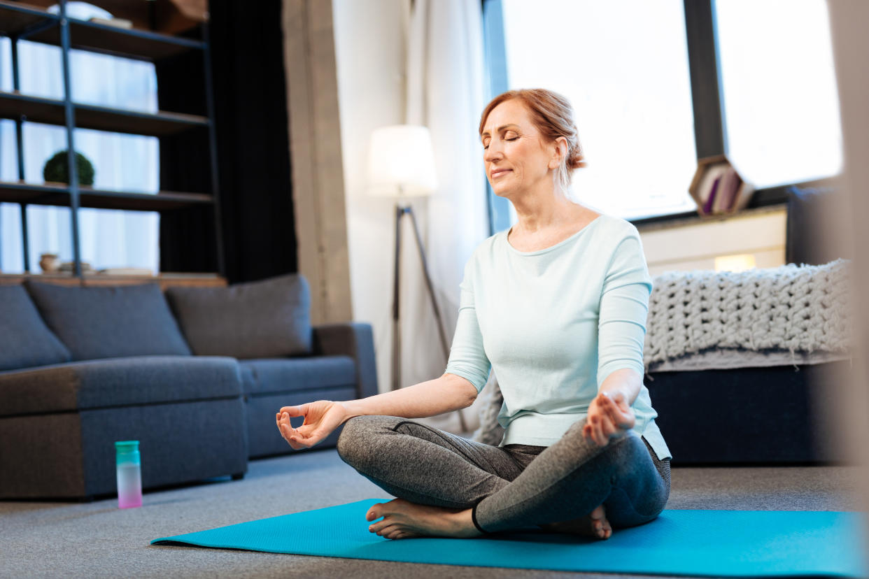 Morning meditation. Tranquil good-looking woman meditating with closed eyes while having connected fingertips