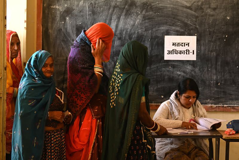 Women wait in a queue to cast their votes at a polling station in Ajmer