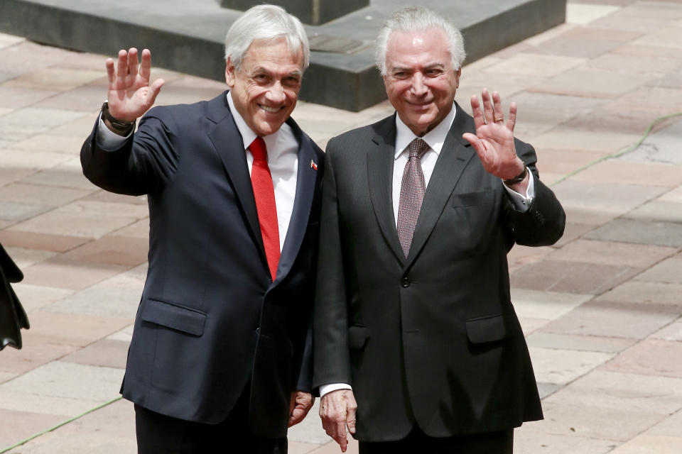 El presidente de Chile, Sebastián Piñera, a la izquierda, y su par de Brasil, Michel Temer, saludan a los periodistas durante una ceremonia de bienvenida en el Palacio Presidencial de La Moneda, en Santiago de Chile, el miércoles 21 de noviembre de 2018. (AP Foto / Esteban Félix)