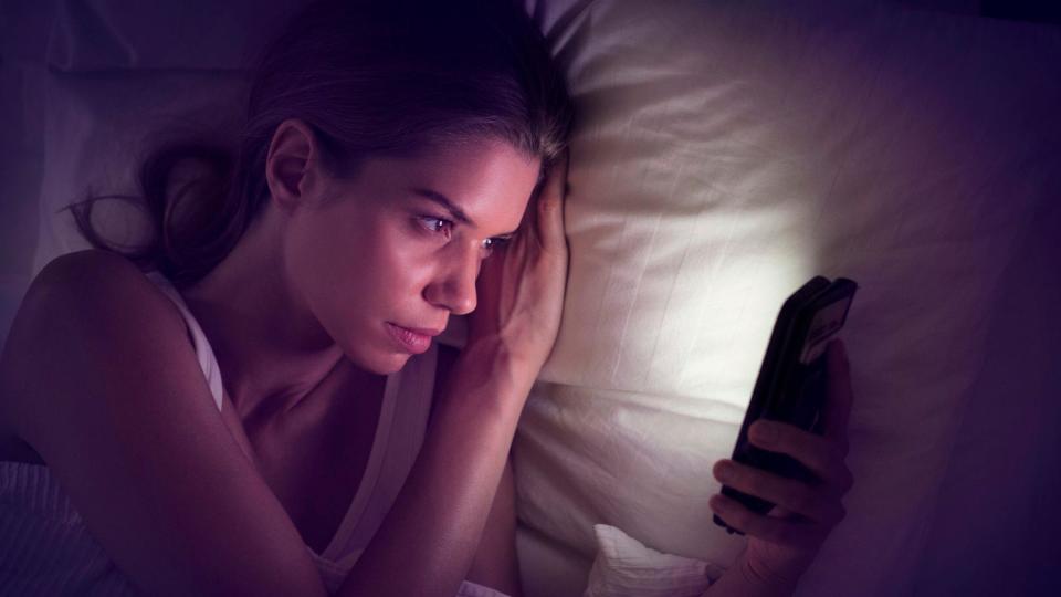 Joven con un celular en la cama 